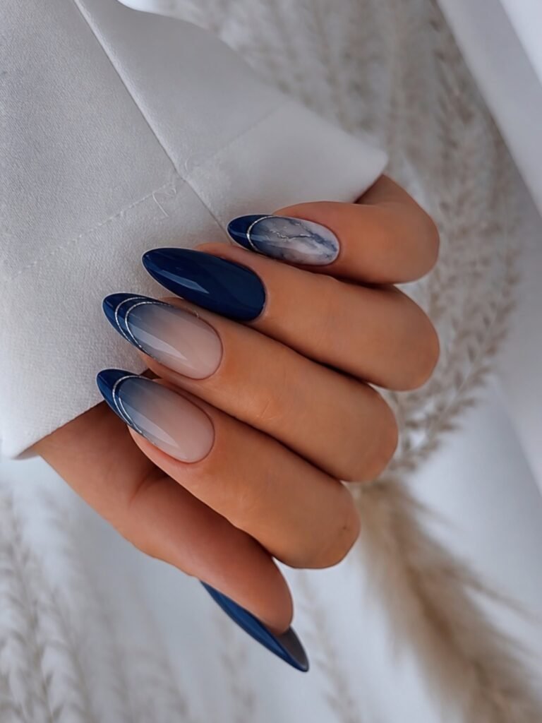 Long almond nails with deep blue cat eye tips and marble accent. 