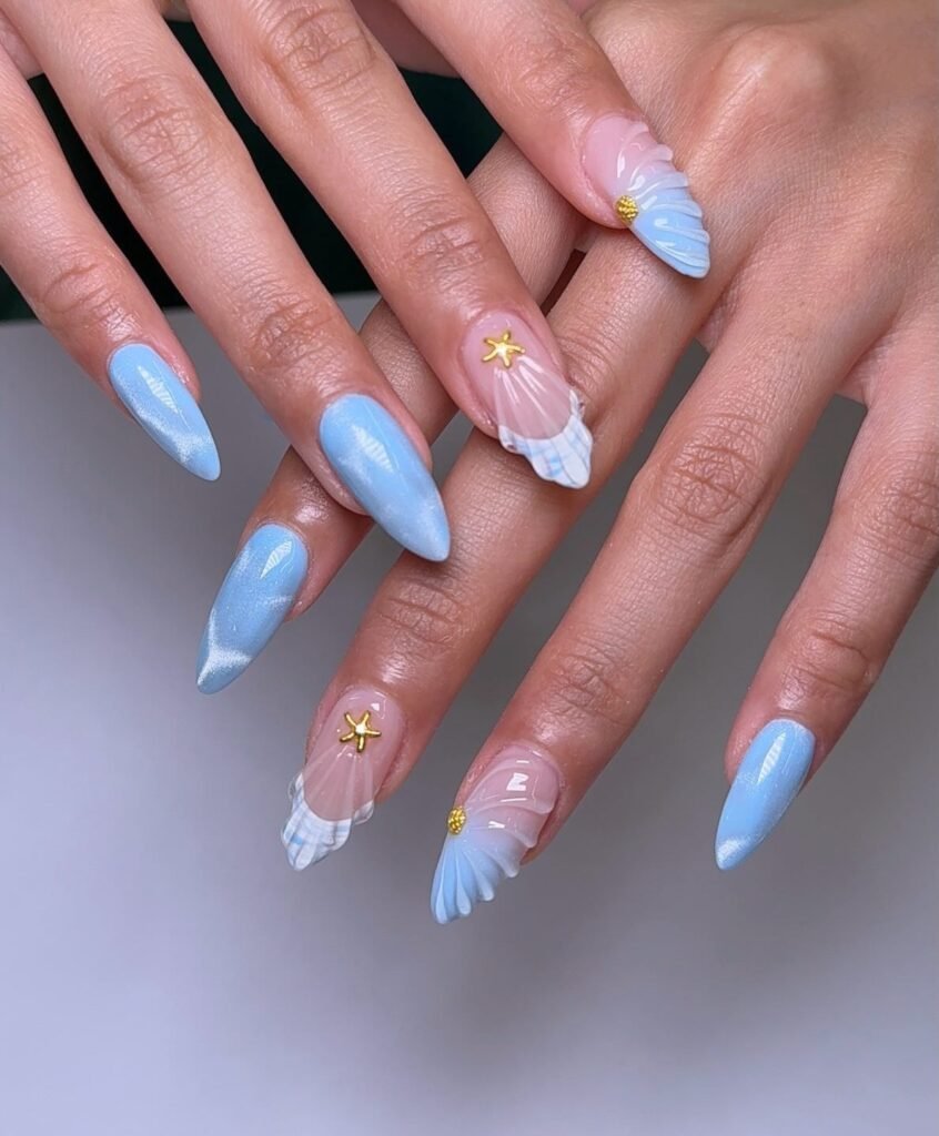 Pastel blue almond nails with seashell accents and tiny gold details.  