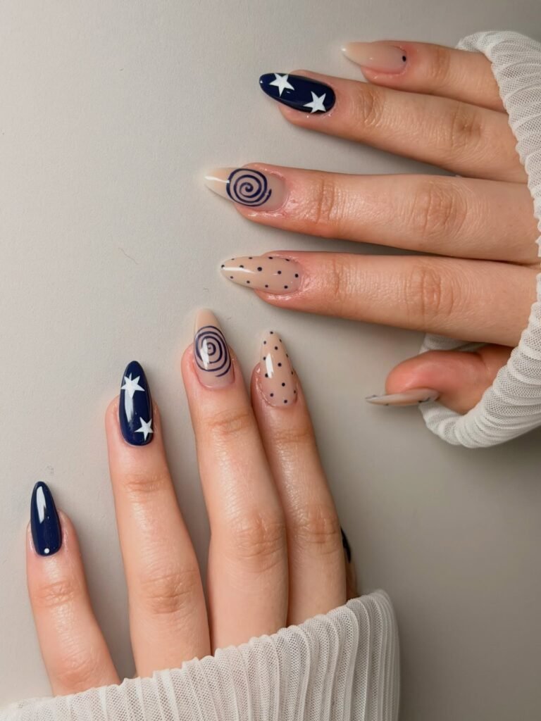 Nude and navy nails with stars, swirls, and tiny dotted accents. 