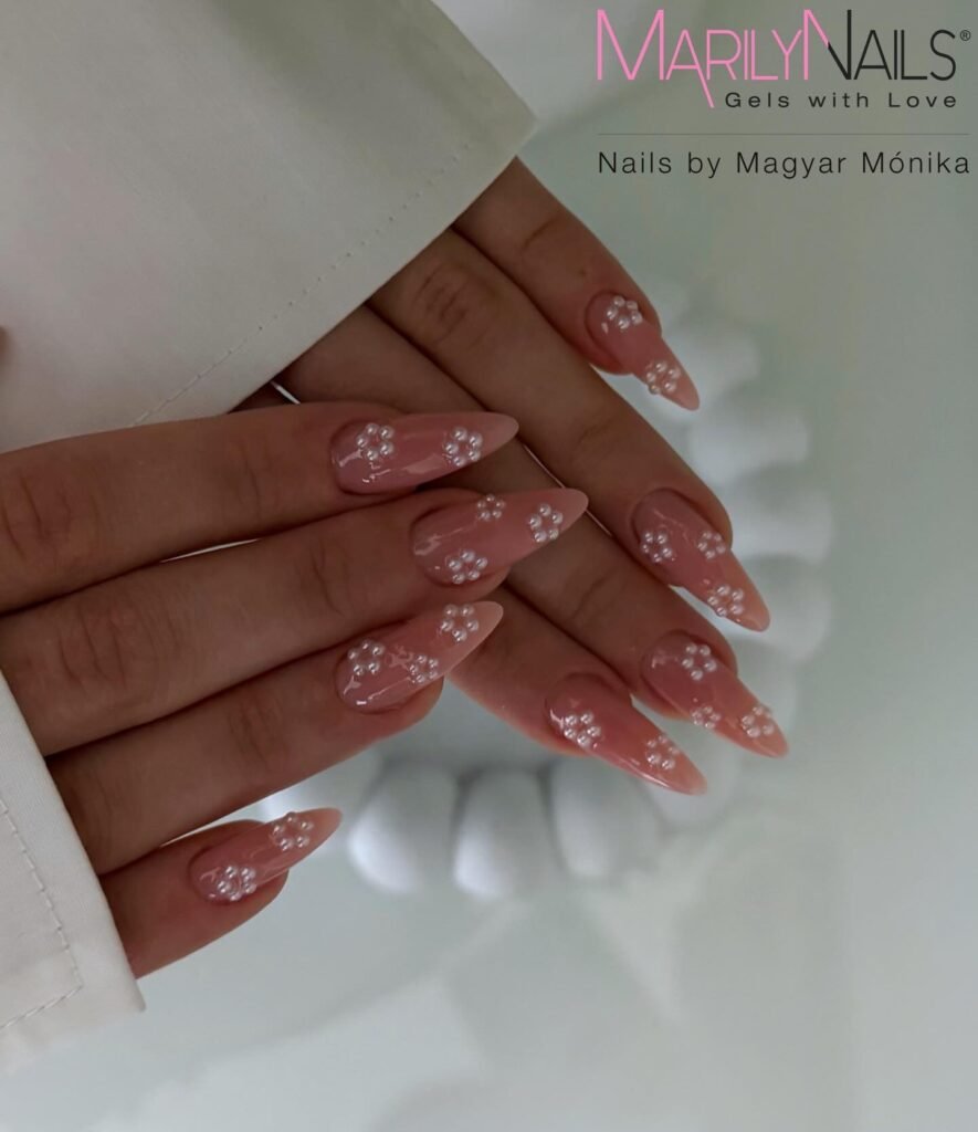 Soft pink almond nails with tiny pearl flowers and glossy finish.  