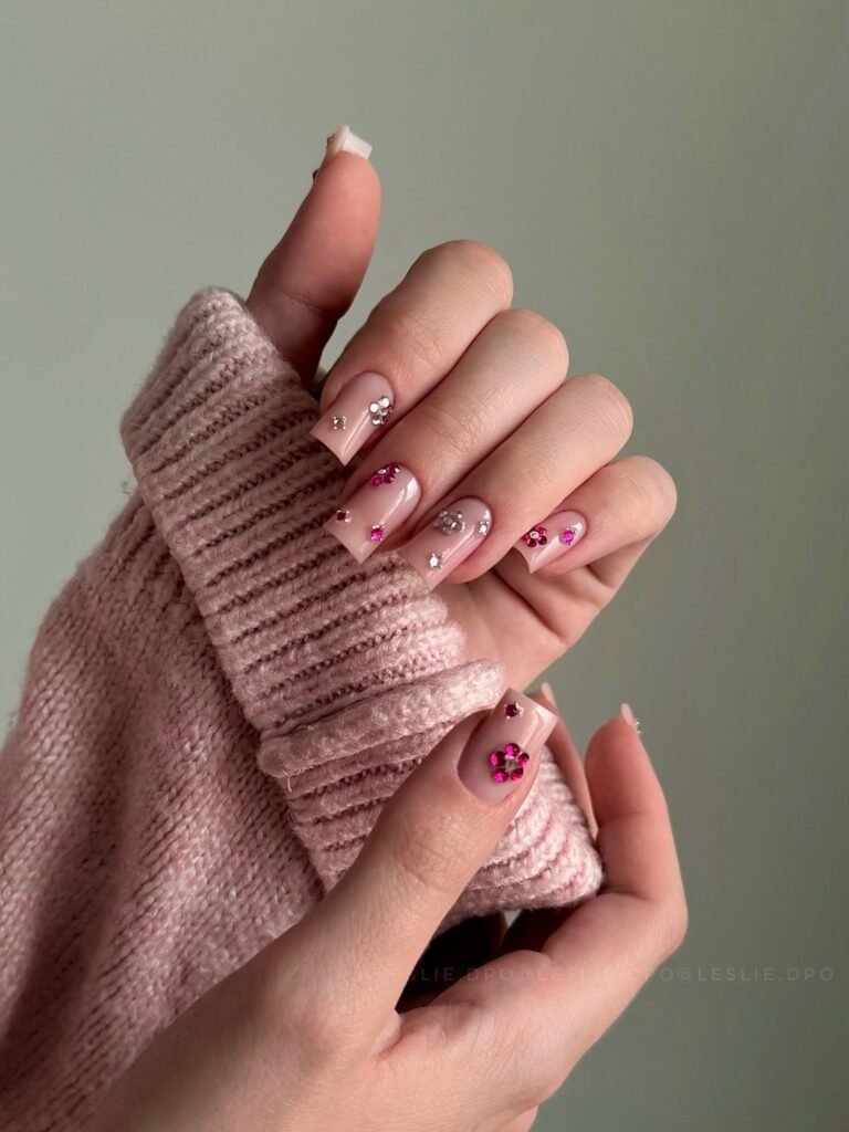  Short blush square nails with tiny rhinestone flowers on a neutral knit.  