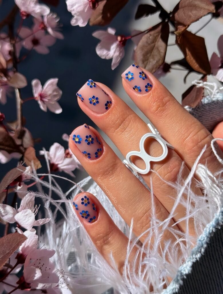Sheer nude square nails with tiny cobalt blue floral details.  