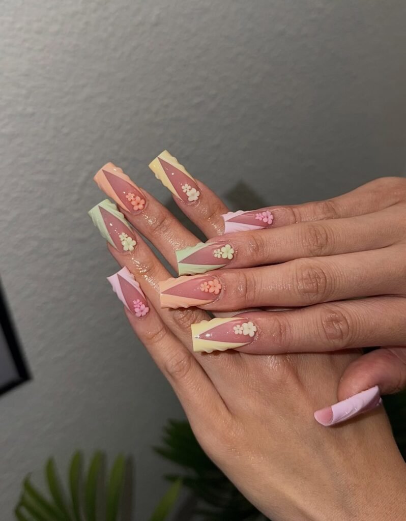 Pastel French tip nails with small floral designs and soft color-blocking on long shape.
