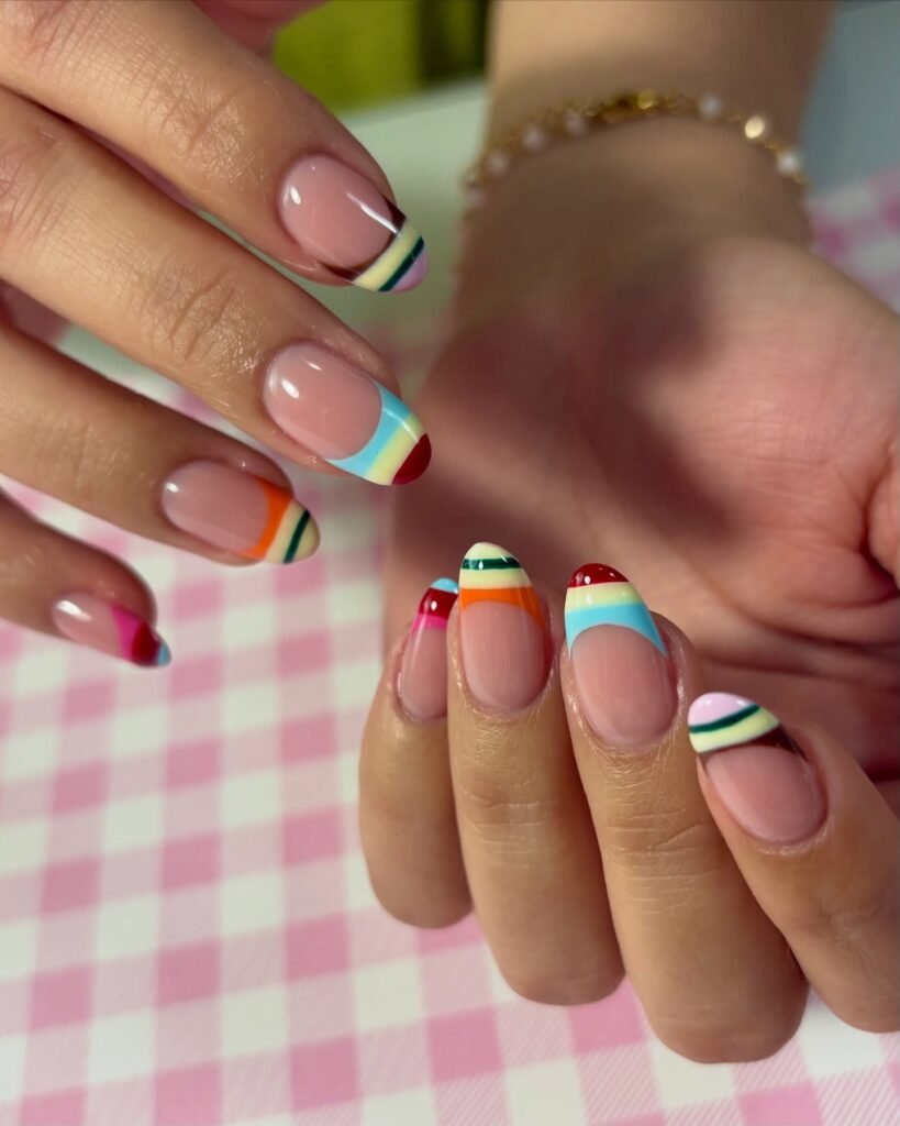Short French tip manicure with rainbow striped color blocks and clean nude base  