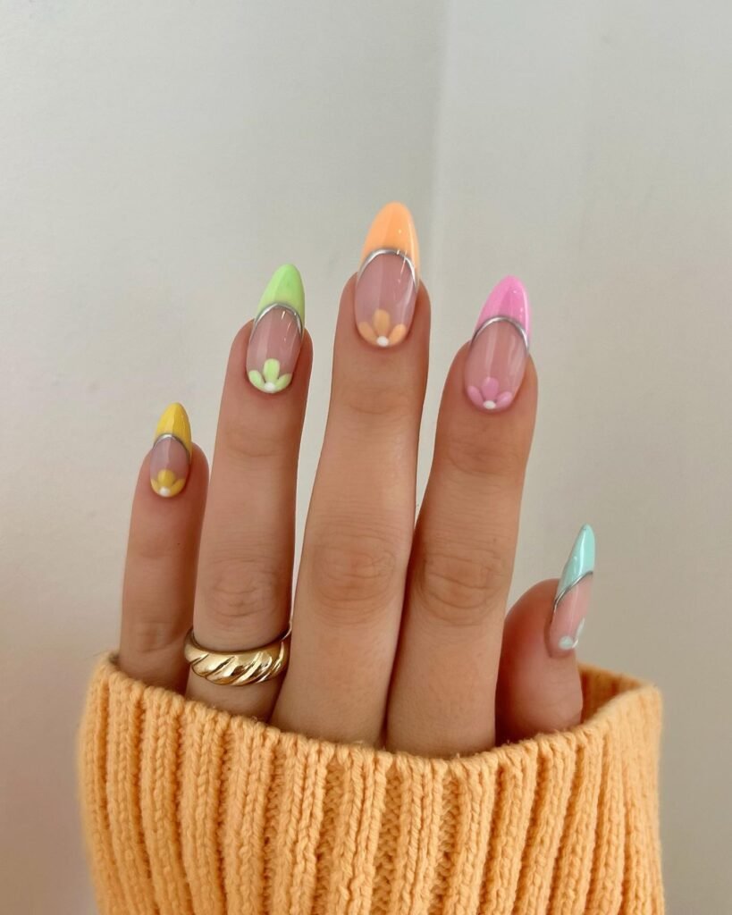 Long nude nails with colored half-moon tips and small flower nail art.