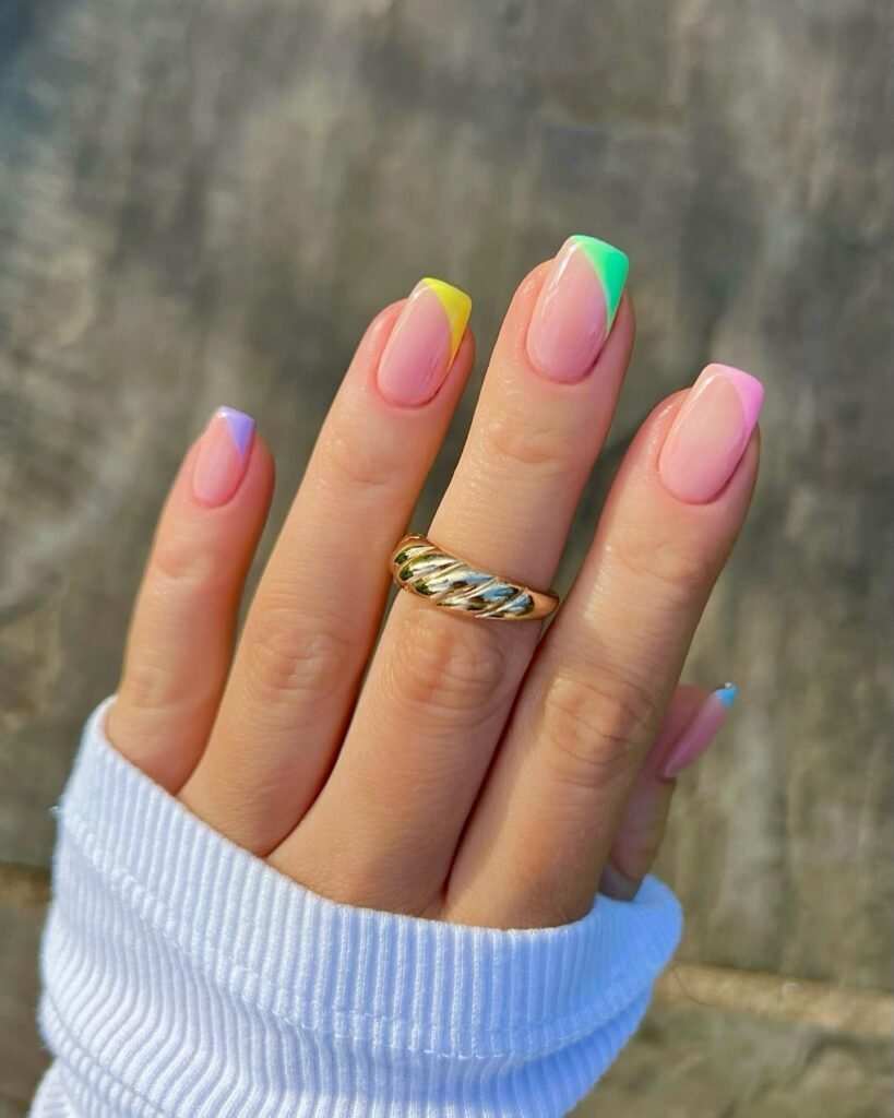 Nude nails with small colorful French tip corners in green, pink, orange, and blue  