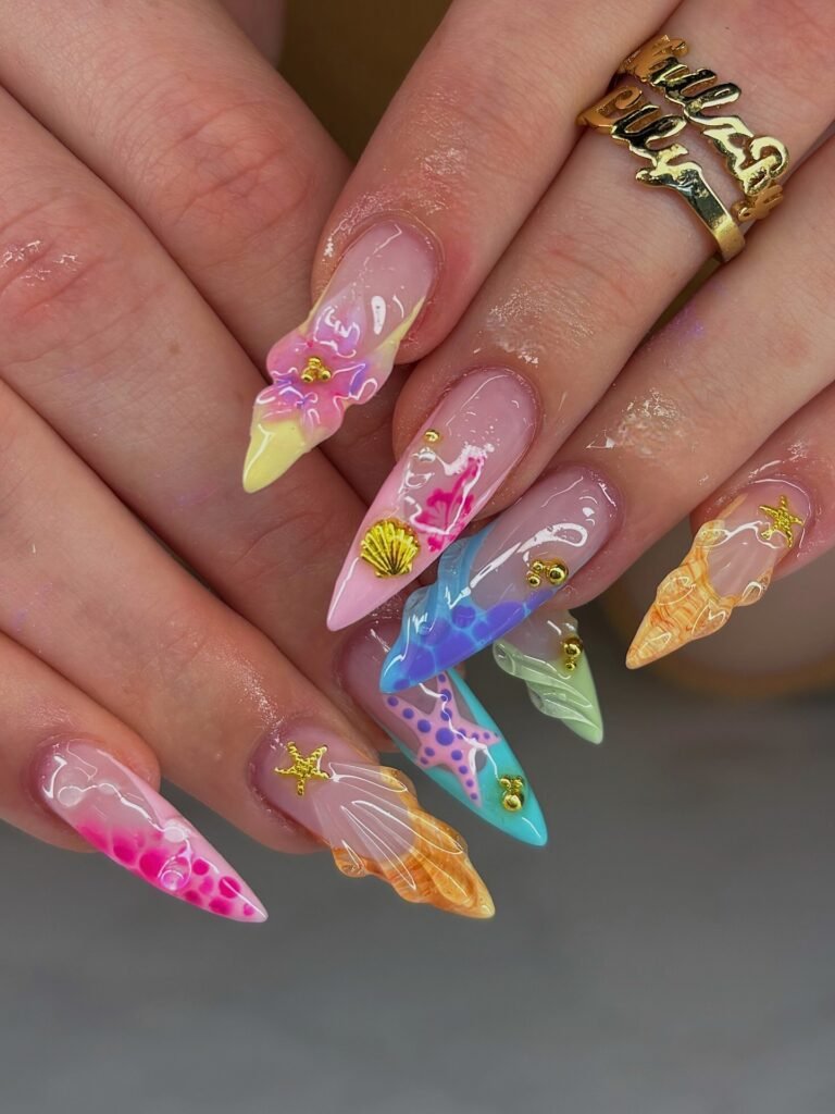 Colorful mermaid French tip nails with starfish, seashells, and gem accents on nude base 
