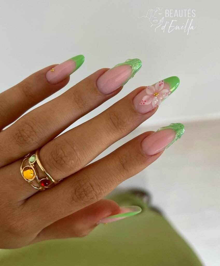Soft pink almond nails with gold French tips and raised floral accents.