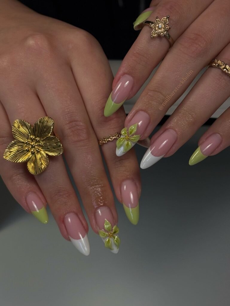 Nude almond nails with lime tips, gold details, and flower accents. 