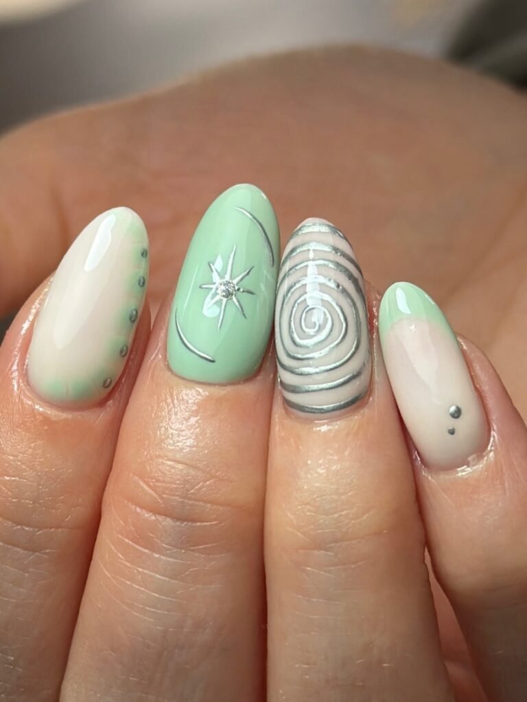 Short mint and cream nails with silver lines and abstract swirl art. 
