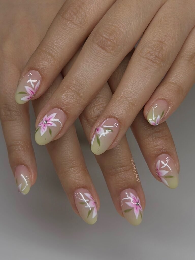 Almond nails with pink flowers, pale yellow tips, and delicate white details. 