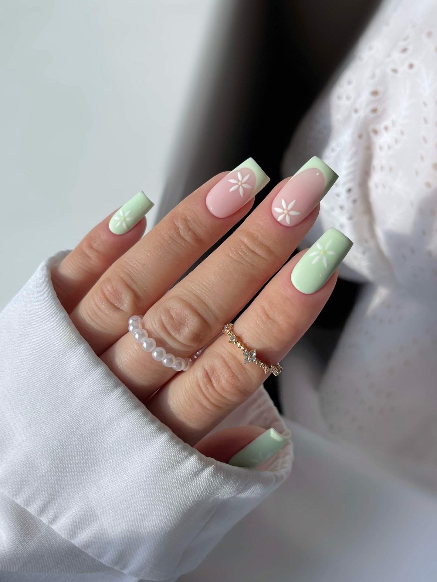 Square pastel nails with mint French tips and small white daisies.