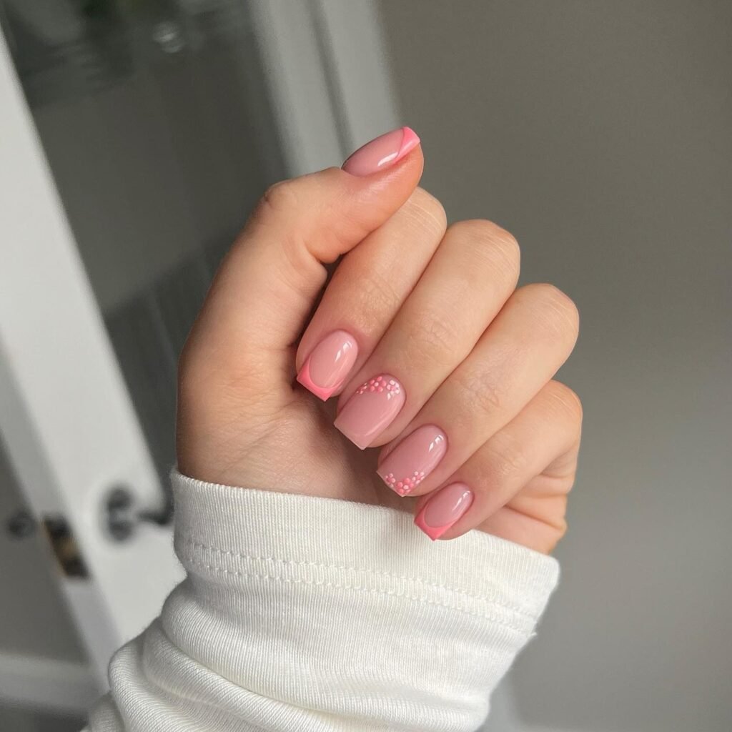 Glossy pink nails with coral tips and tiny floral accents.