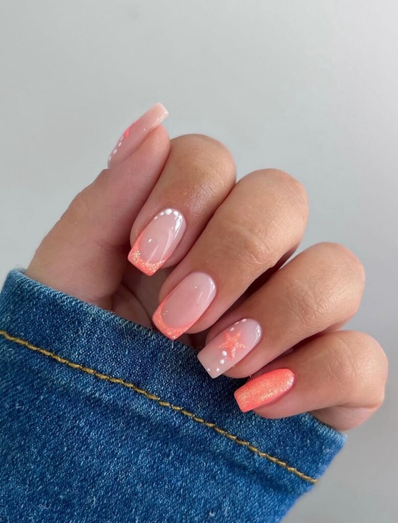Glossy nude nails with coral glitter French tips and star accents.  
