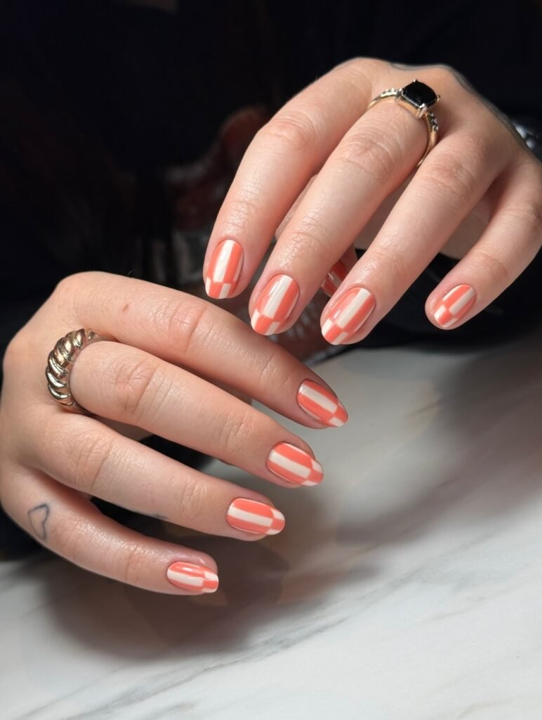  Short oval nails with coral and white striped geometric patterns.  