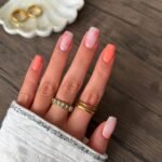 Short square nails with coral polish and tiny floral accent art