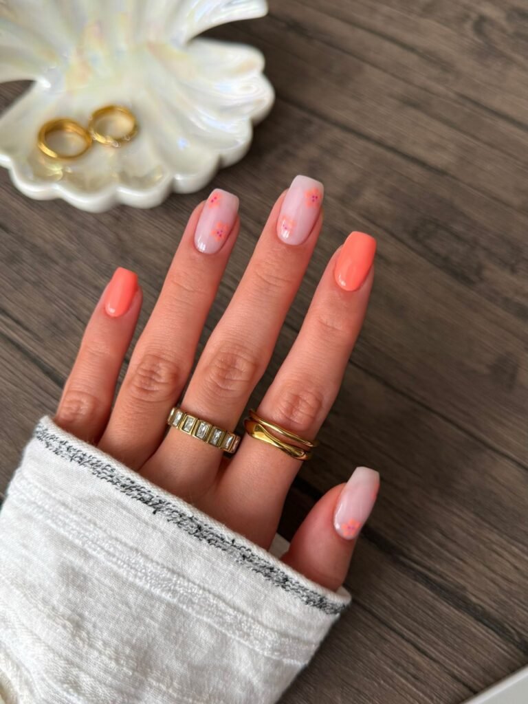  Short square nails with coral polish and tiny floral accent art.  