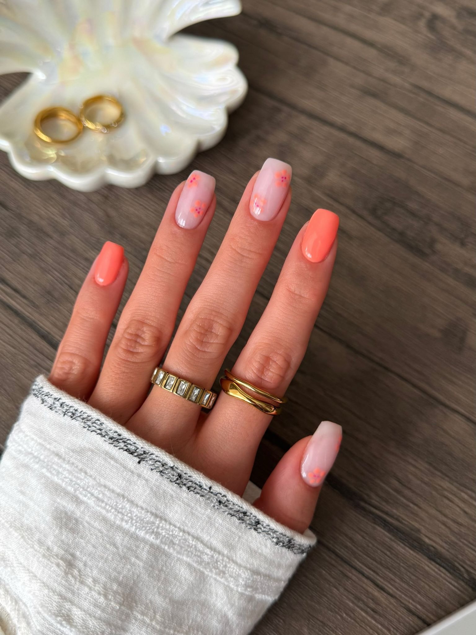 Short square nails with coral polish and tiny floral accent art