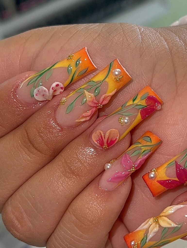 Long square nails with orange French tips, green leafy line art, and delicate floral details.