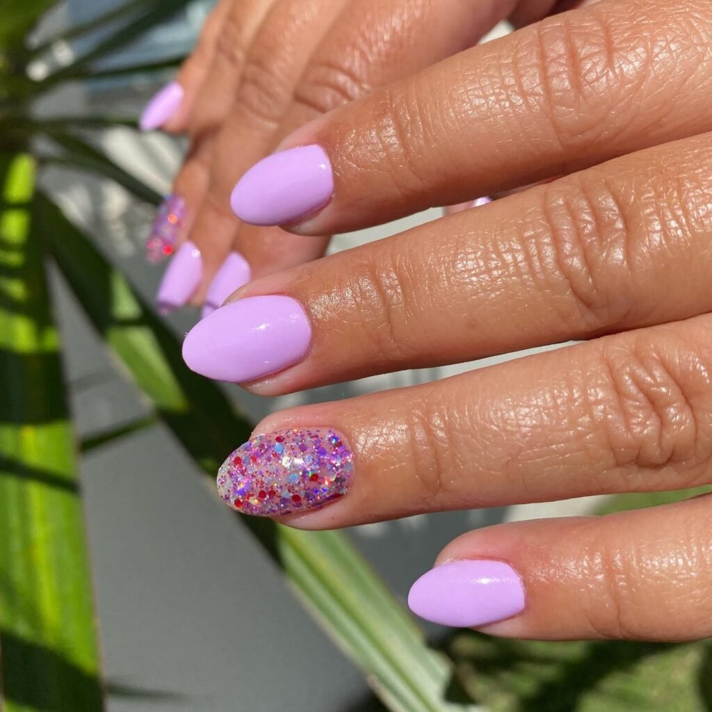 Glossy lilac almond nails with one sparkling glitter accent finger.
