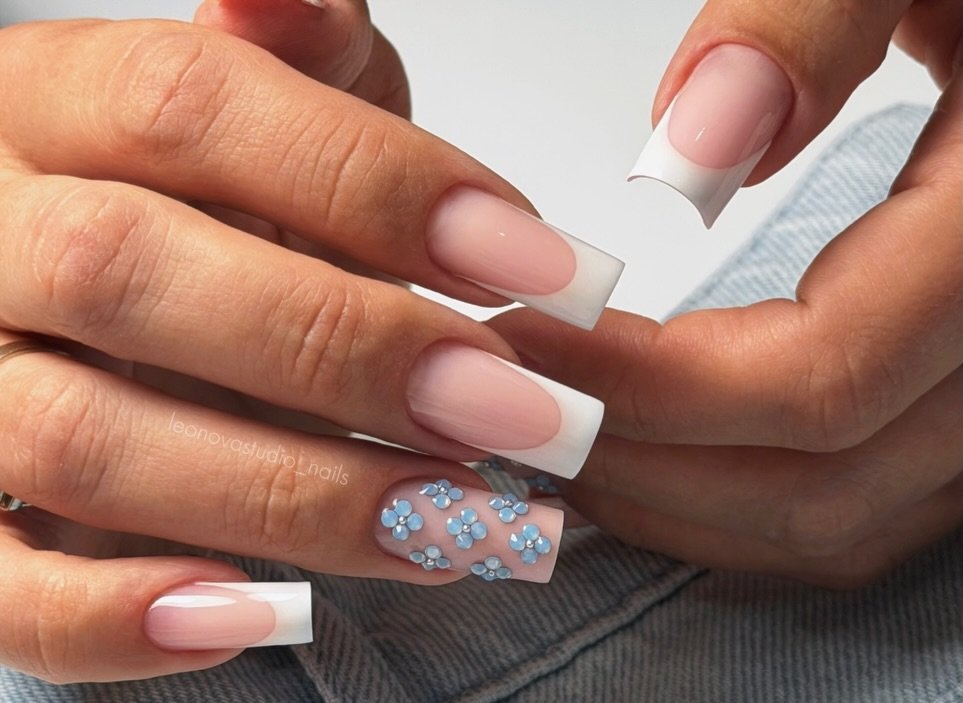 Nude square French manicure with delicate blue floral accent nail art.  