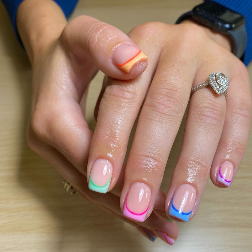 Short rainbow French tip nails on glossy nude base