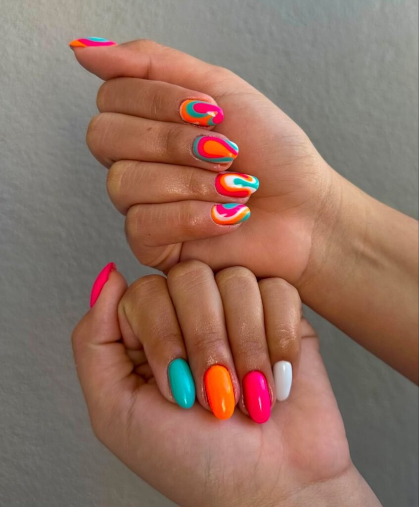 Bright summer skittle nails with rainbow swirl accent hand
