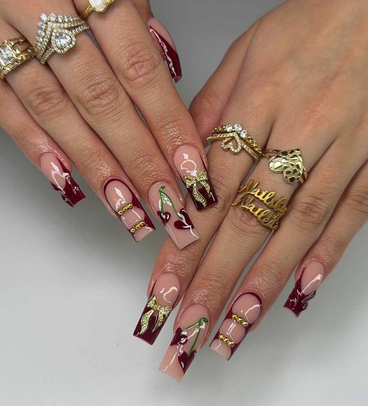 burgundy cherry nails with gold bows and glossy tips
