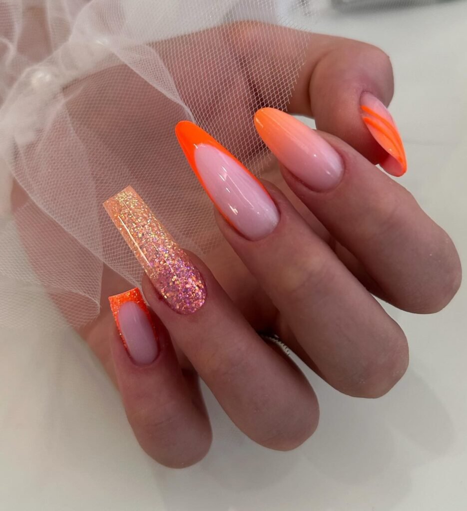 Orange French tip sunset nails with glitter accent
