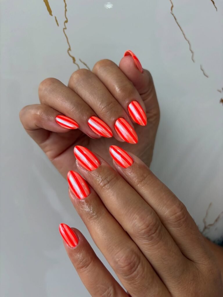 Coral striped nails with white lines on short almond nails
