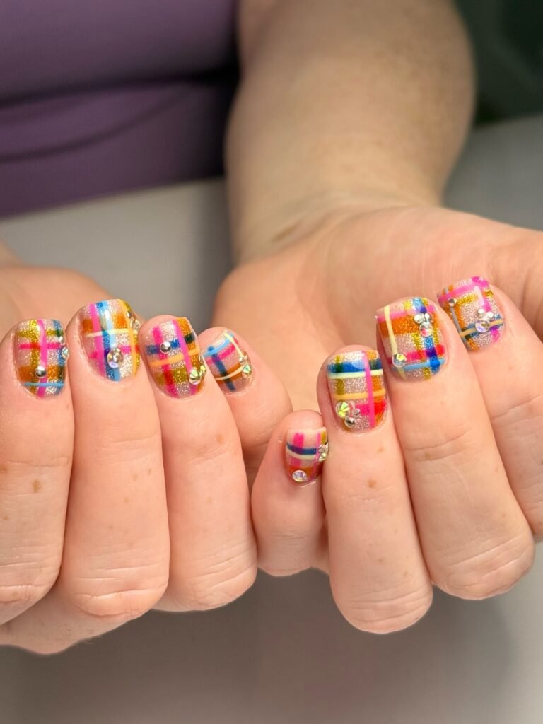 colorful plaid nails with glitter base and rhinestones